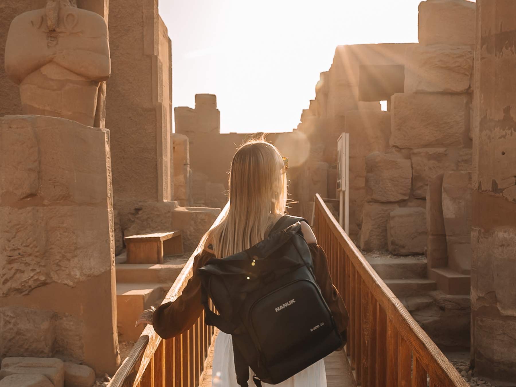 Person with a backpack walking through ancient stone ruins