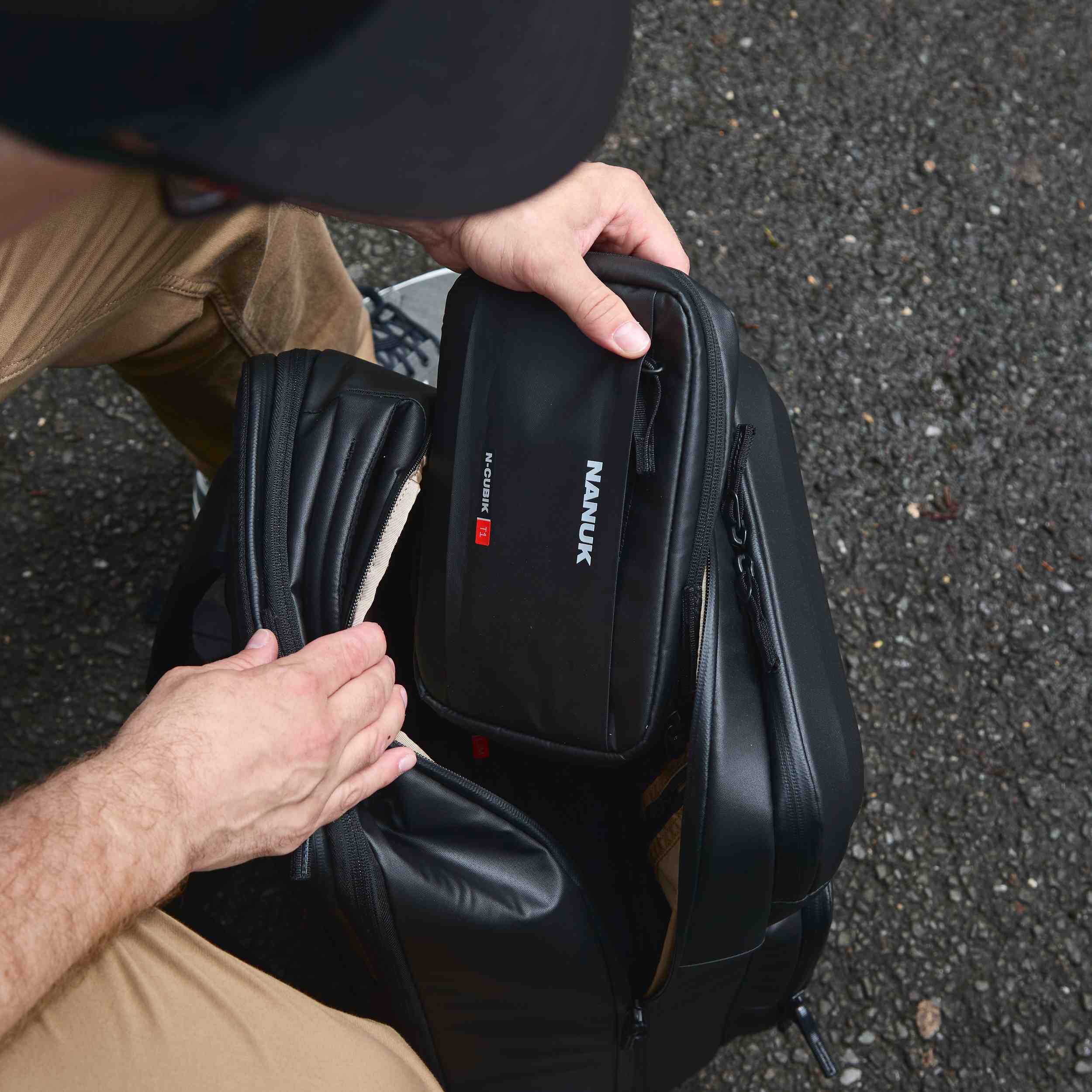 Person holding a black Nanuk backpack with a knife sheath on a textured surface Person holding a black Nanuk backpack with a knife sheath on a textured surface