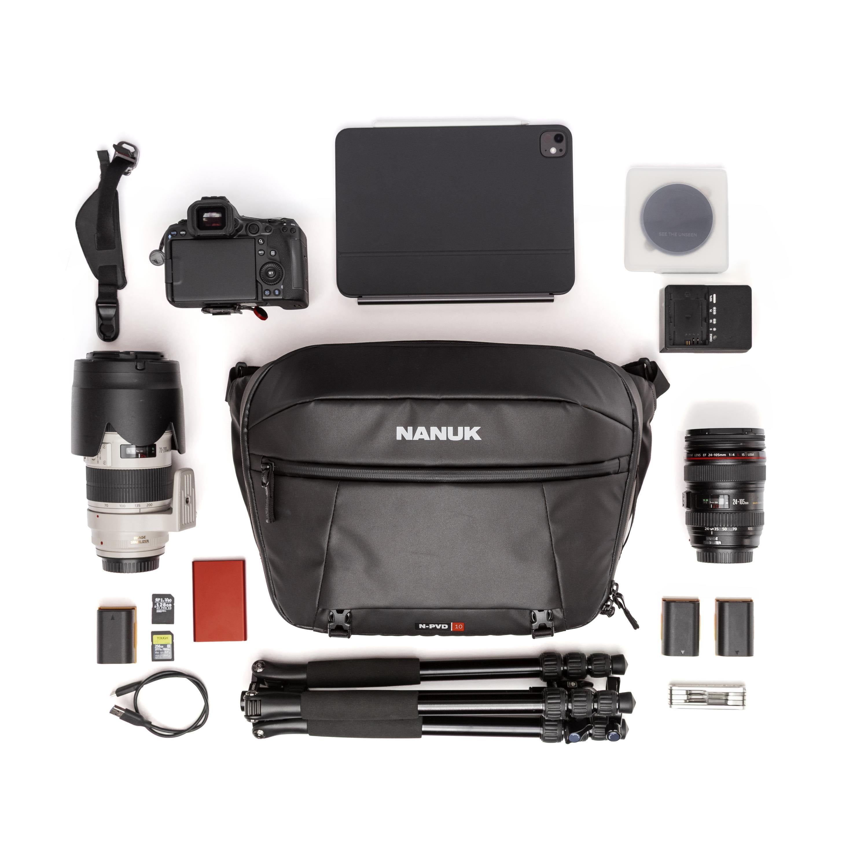 A flat-lay product presentation of a black Nanuk SLR Pro 20 camera bag surrounded by various photography accessories, including a DSLR camera, lenses, tripod, tablet, battery, and cards, on a solid white background. A flat-lay product presentation of a black Nanuk SLR Pro 20 camera bag surrounded by various photography accessories, including a DSLR camera, lenses, tripod, tablet, battery, and cards, on a solid white background.