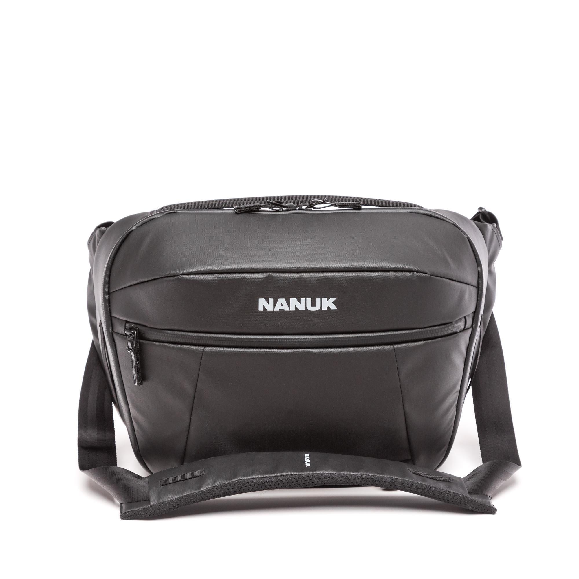 A black Nanuk messenger bag with a front zippered pocket and white brand logo, shown on a clean white background. A black Nanuk messenger bag with a front zippered pocket and white brand logo, shown on a clean white background.