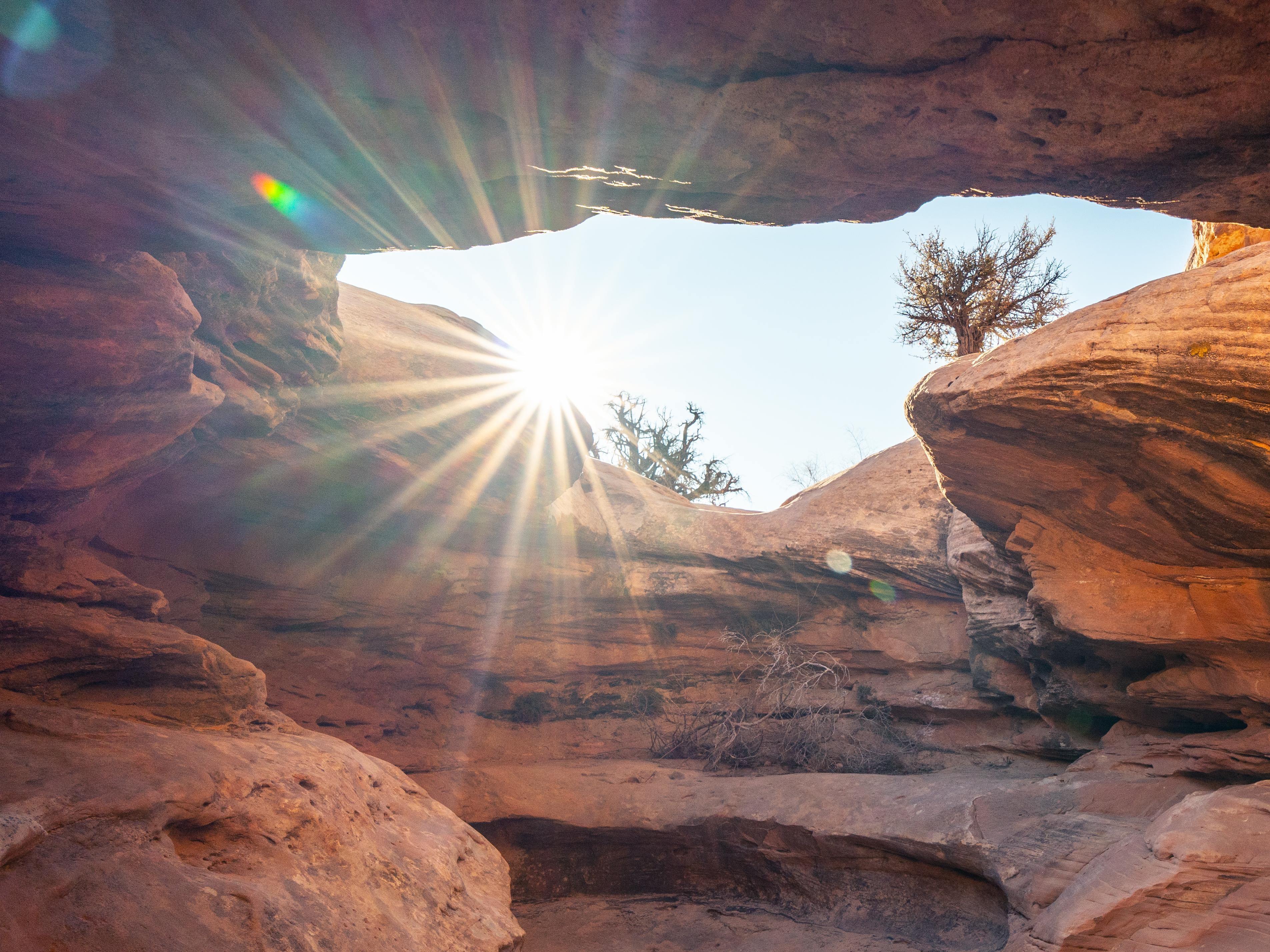 Sun shining through a natural rock arch in a desert landscape