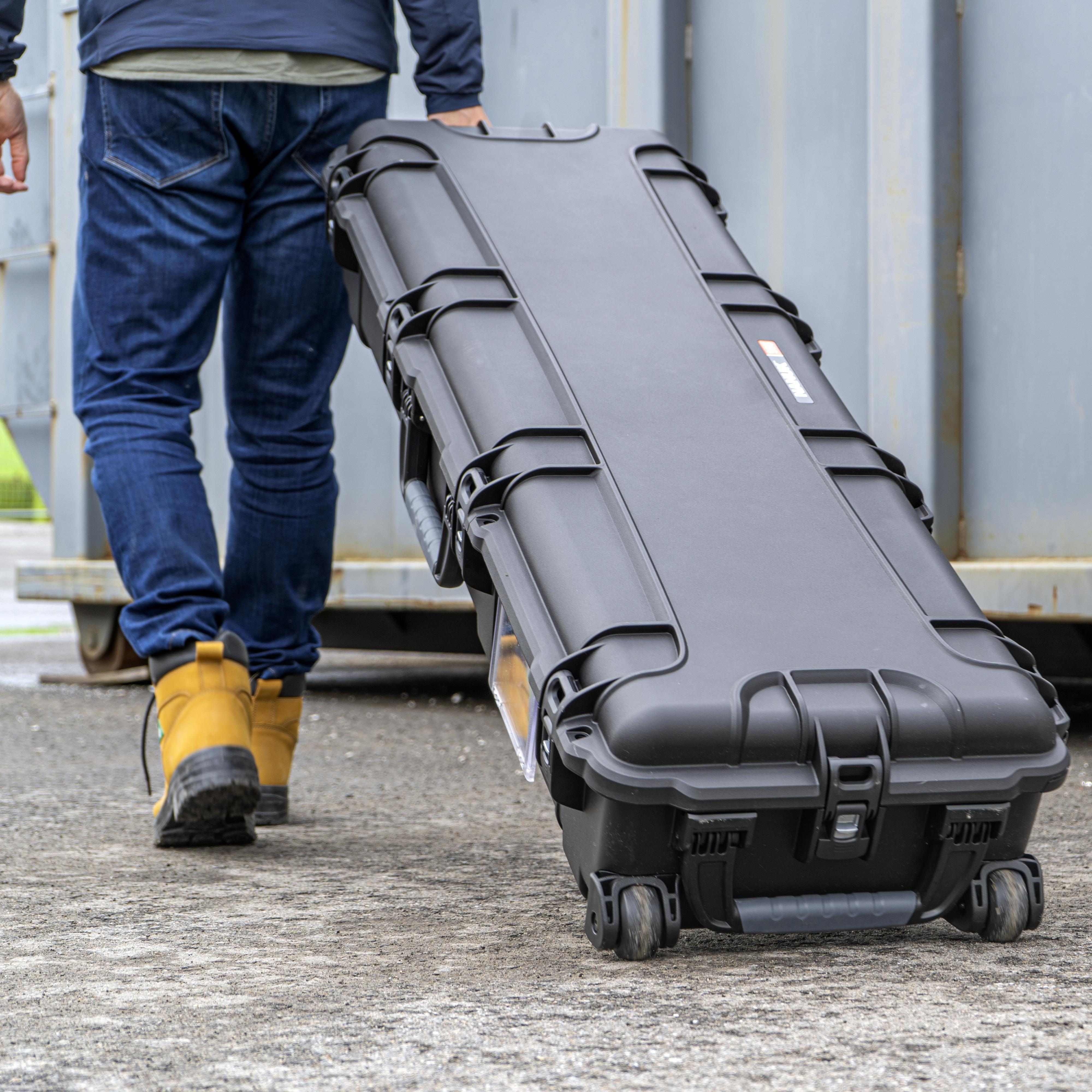 Person walking with a large black hard-shell case outdoors. Person walking with a large black hard-shell case outdoors.