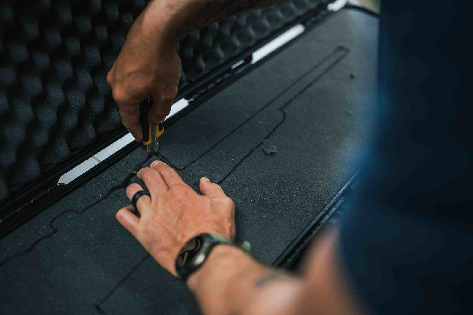 Person using a tool to work on a black surface