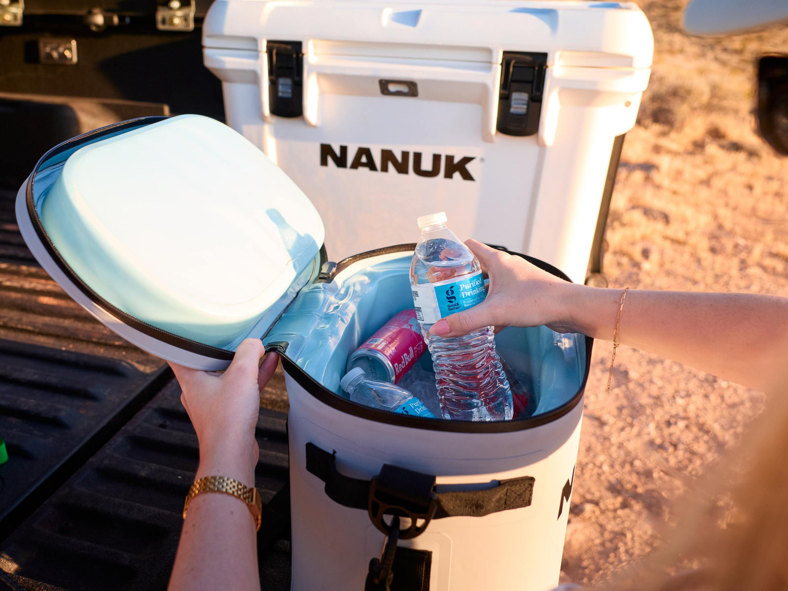 Person opening a Nanuk cooler with drinks inside, outdoors.