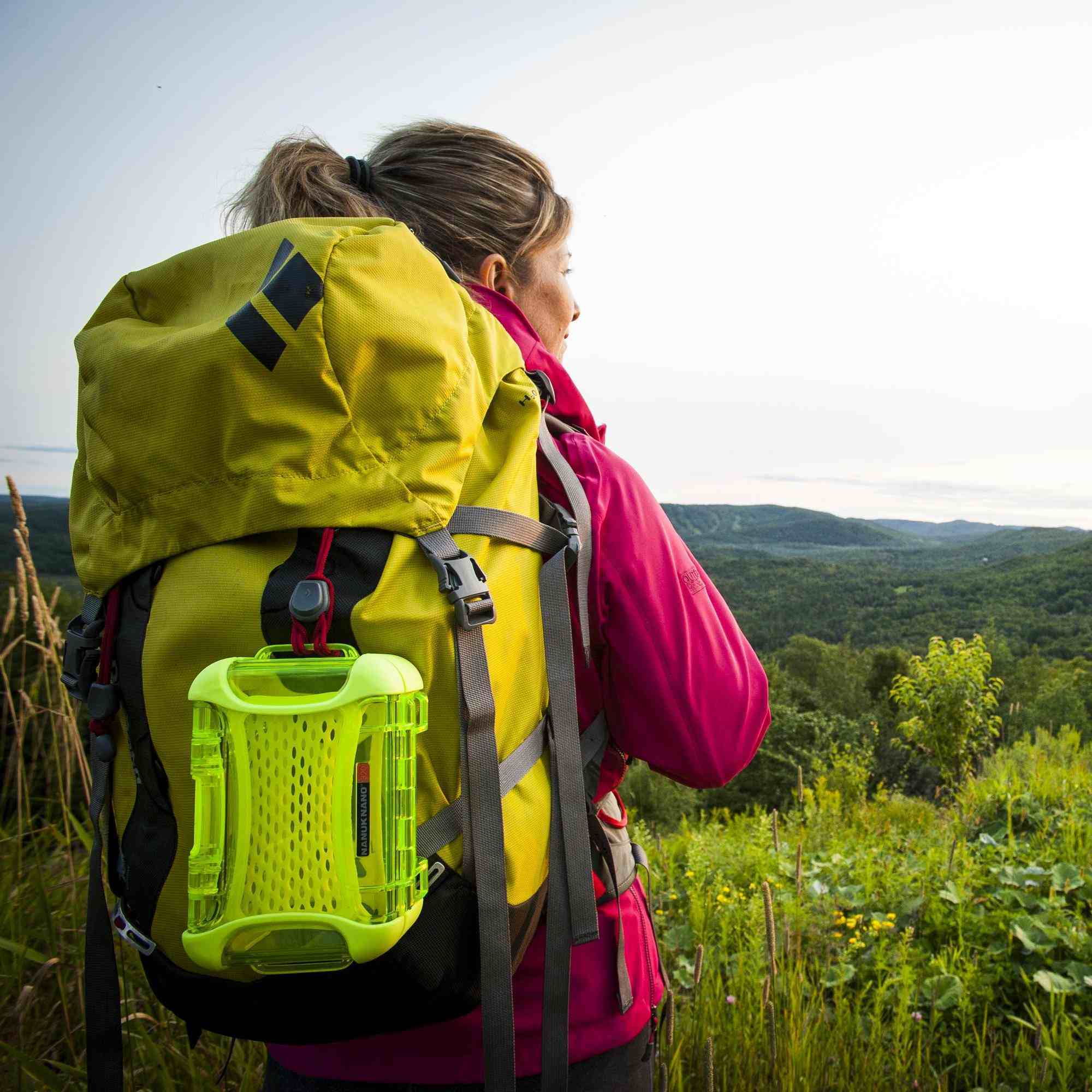 Person with a yellow backpack and pink jacket standing in a scenic outdoor setting. Person with a yellow backpack and pink jacket standing in a scenic outdoor setting.