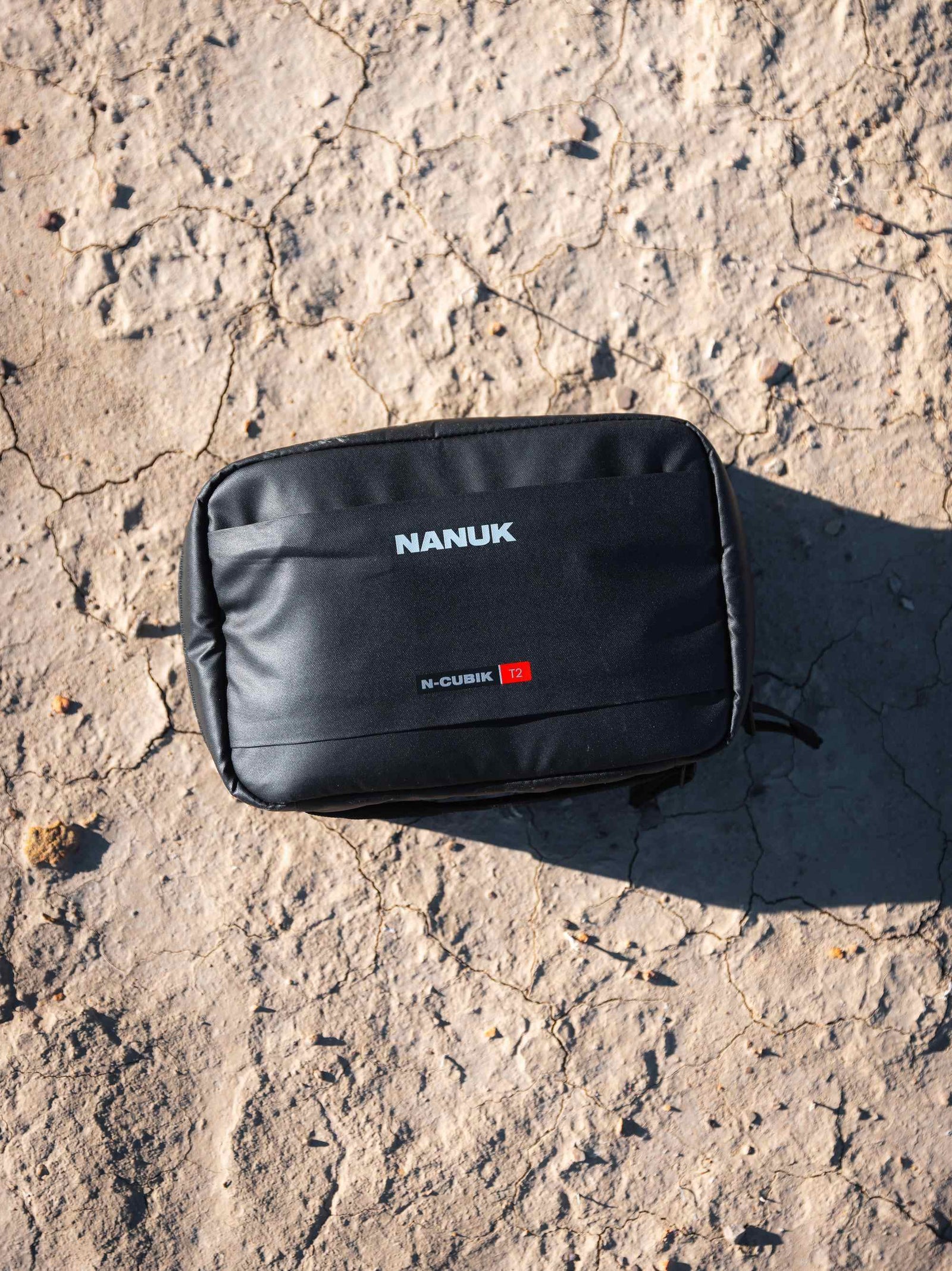 Black Nanuk pouch on a textured concrete surface
