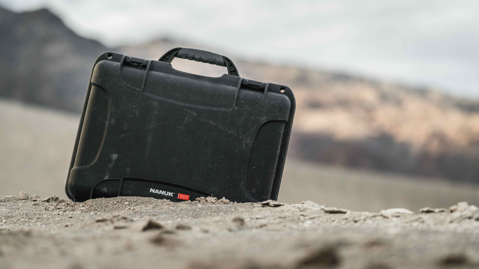 Close-up of a black NANUK 910 case, featuring its durable design and ergonomic handle against a dark background.