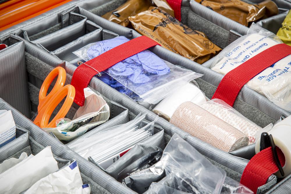 Organized compartments with supplies including scissors, bandages, and other medical items.