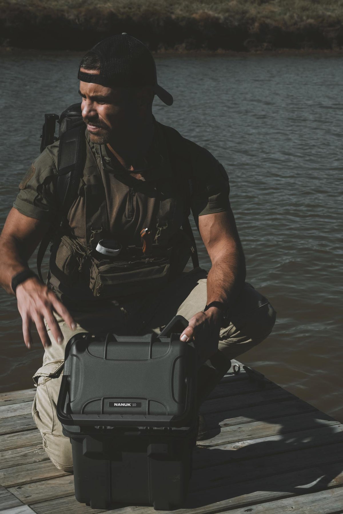 Man sitting by a body of water with a Rugged Radios case