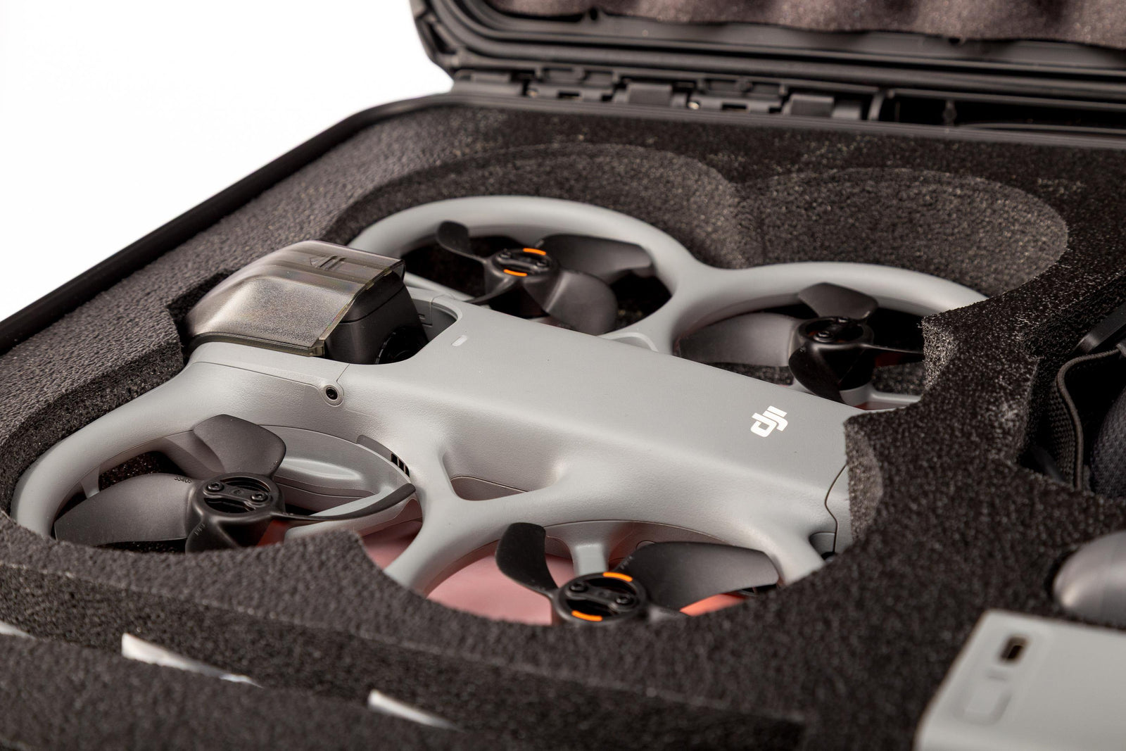 White drone inside a black protective case with a smartphone showing a drone app.