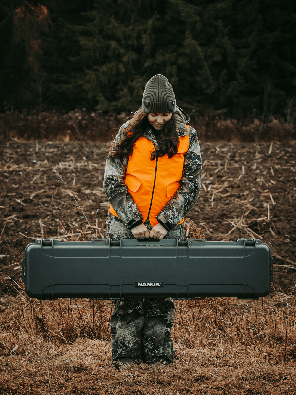 Person holding a large black Nanuk case in a forest setting
