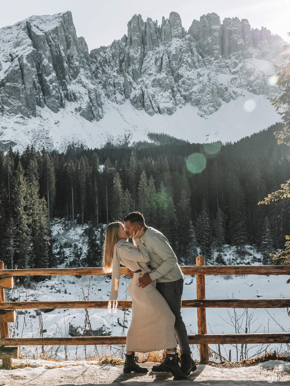 Couple embracing in a snowy landscape with mountains and trees in the background