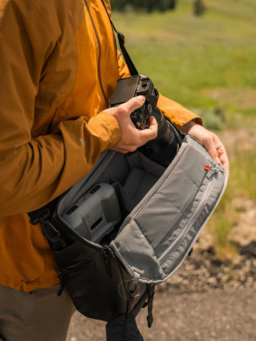 Person holding a camera and open bag with scenic background