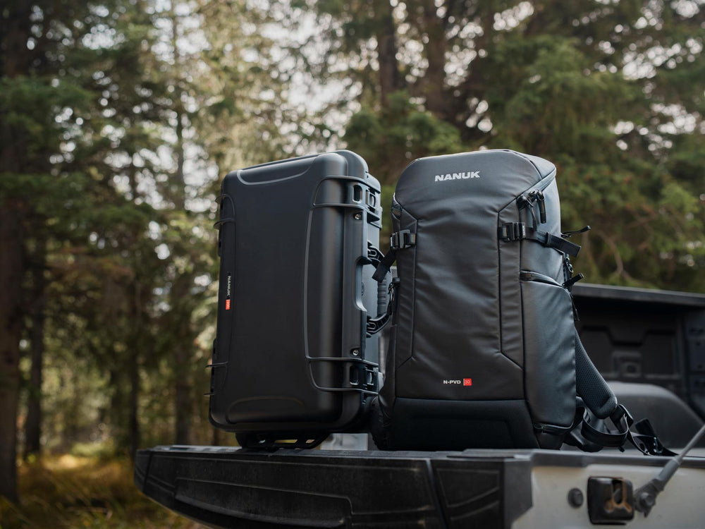 Two black backpacks with visible branding on a truck bed with a forest background