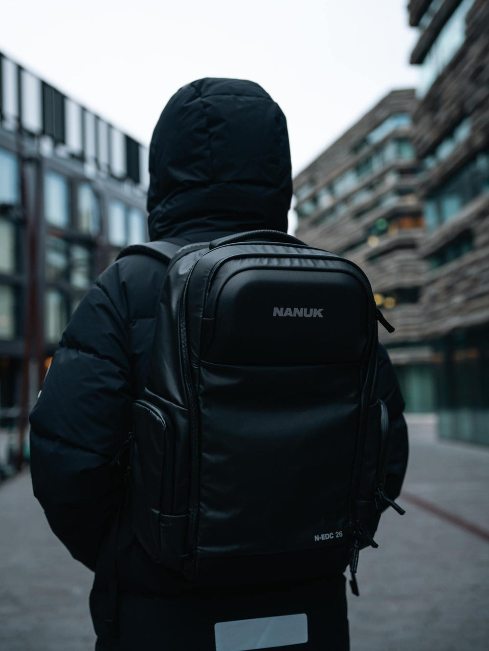 Person wearing a black Nanuk backpack in an urban setting