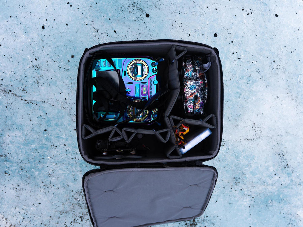 Open black camera bag with camera equipment on a textured blue surface