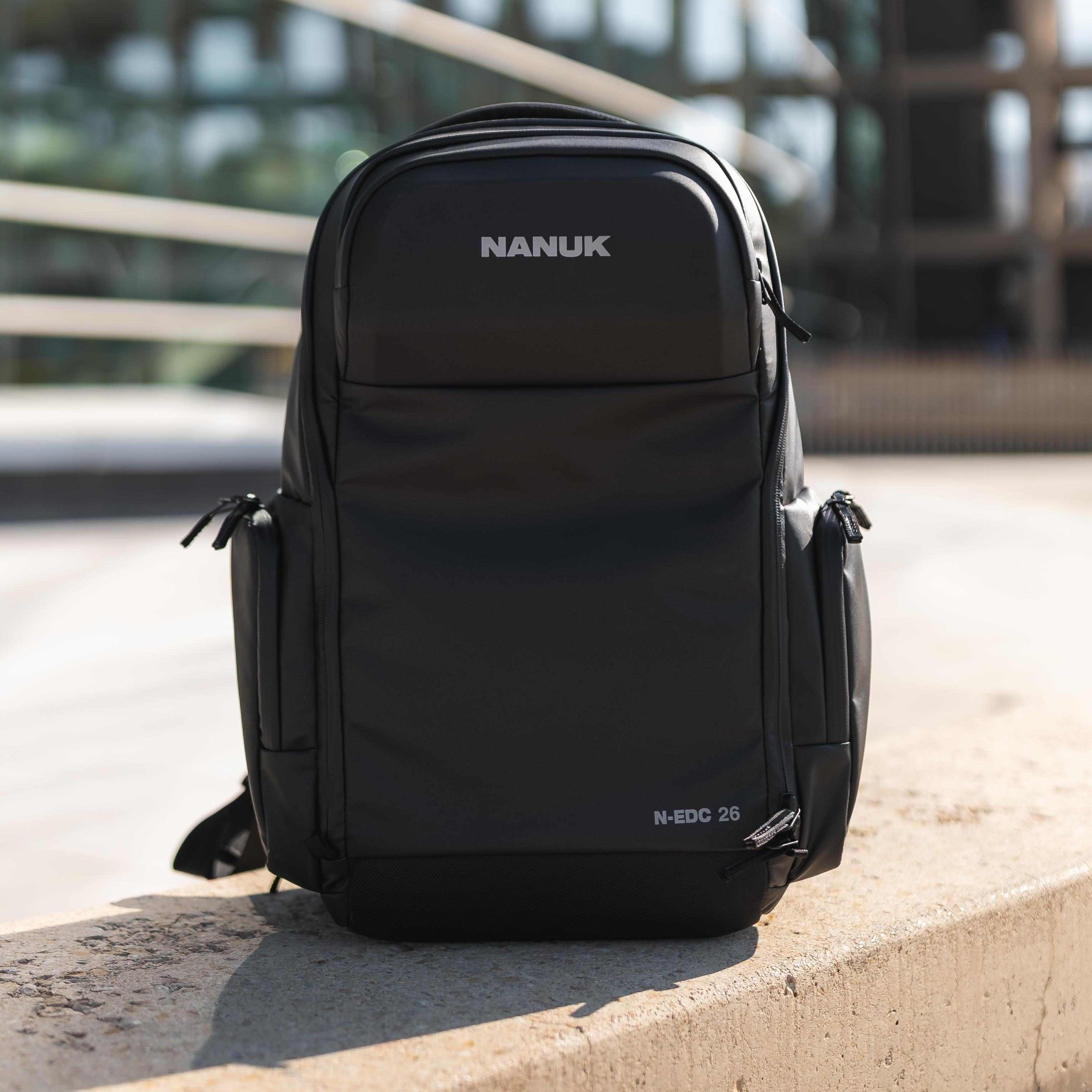 Black Nanuk backpack on a concrete ledge with a blurred background