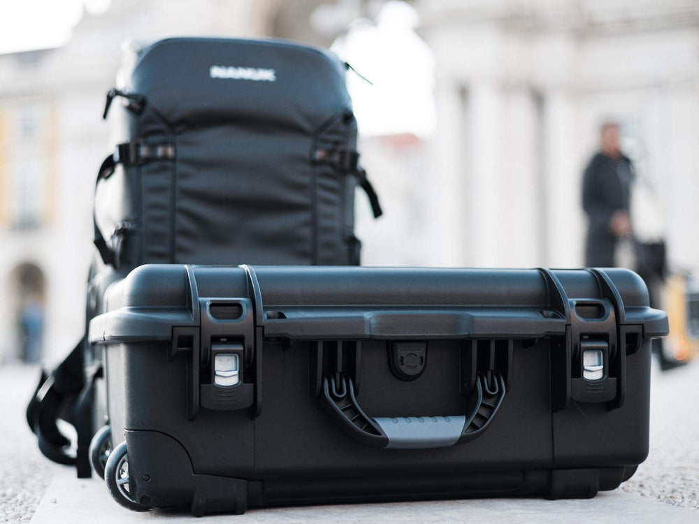 Black suitcase and backpack on a blurred city street background