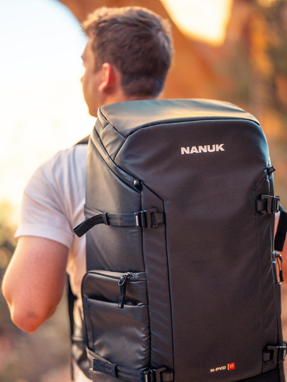 Person wearing a Nanuk backpack with a blurred natural background