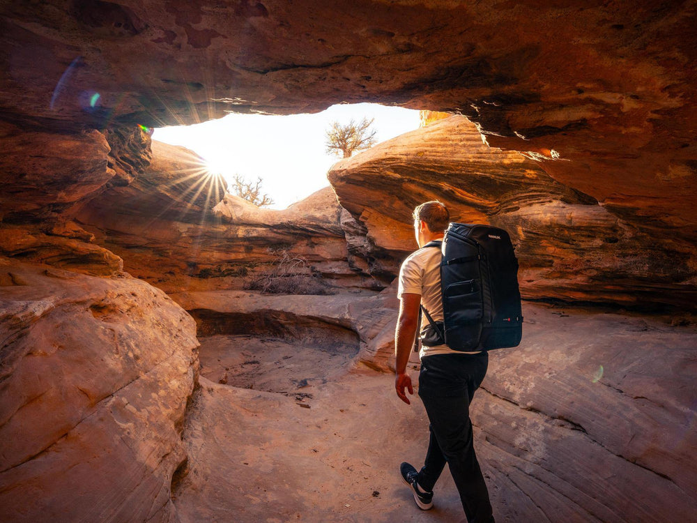 Person with a backpack exploring a rocky cave entrance