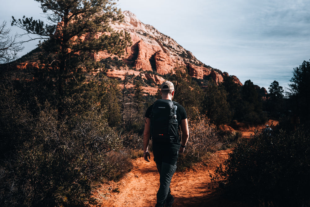 Person hiking on a trail with red rock formations in the background
