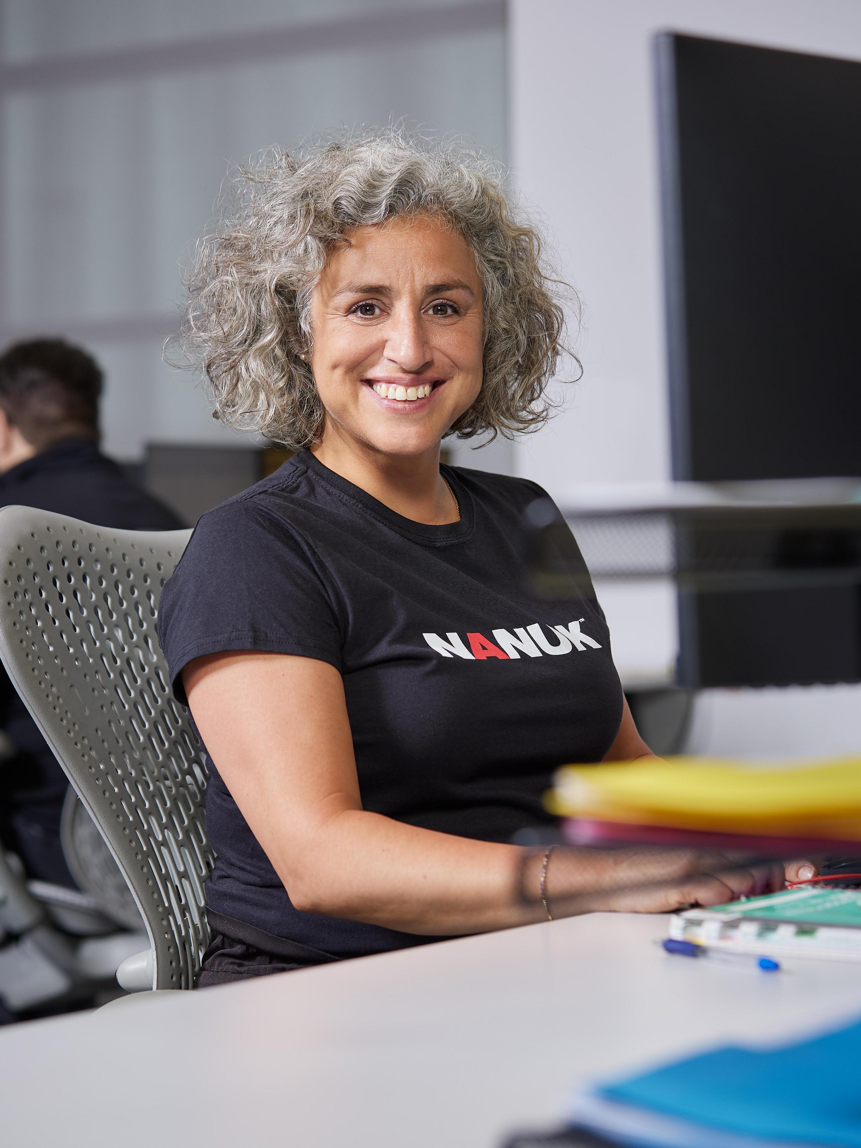 Person wearing a black Nanuk t-shirt sitting at a desk in an office setting.