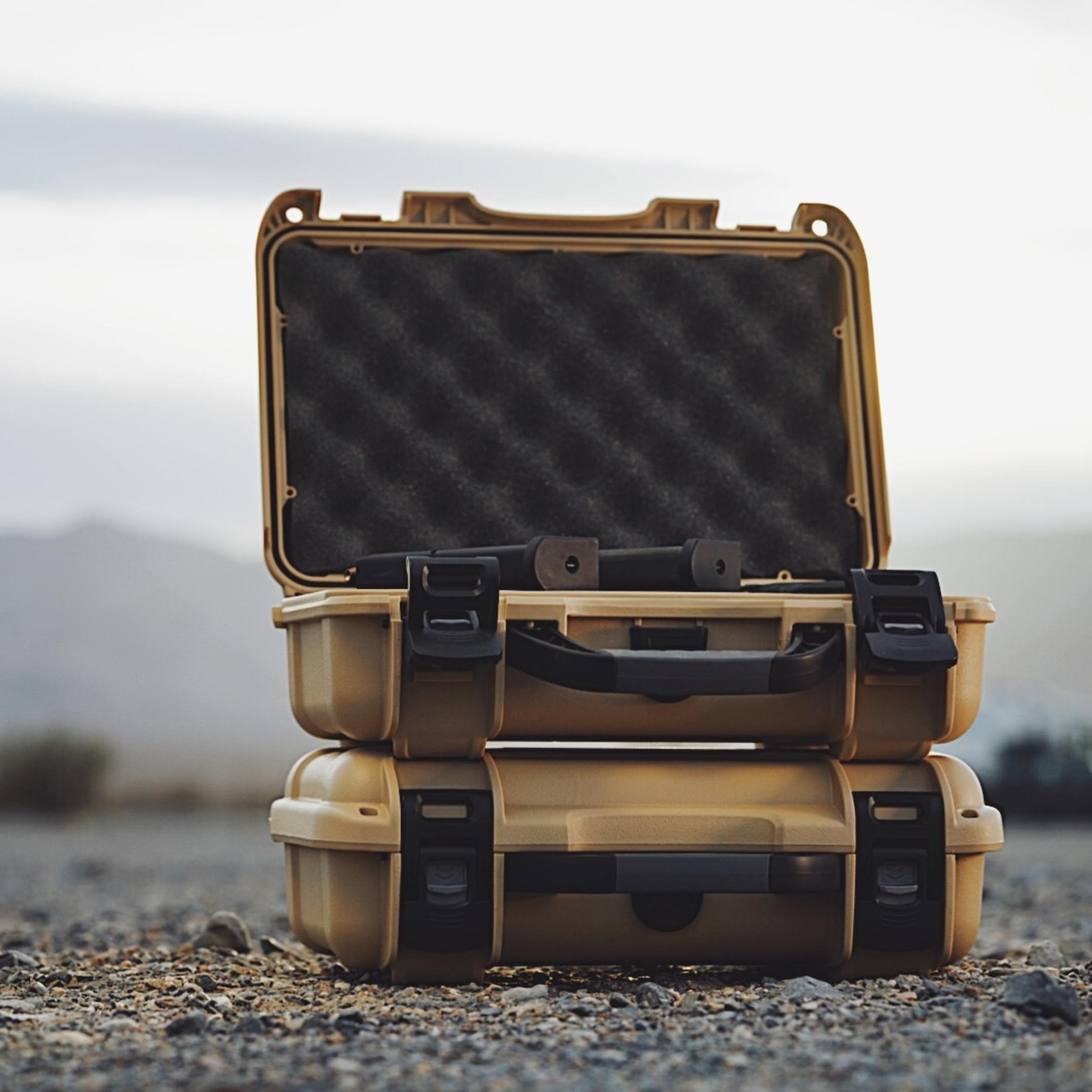 Open beige hard-shell case with black interior on a desert background
