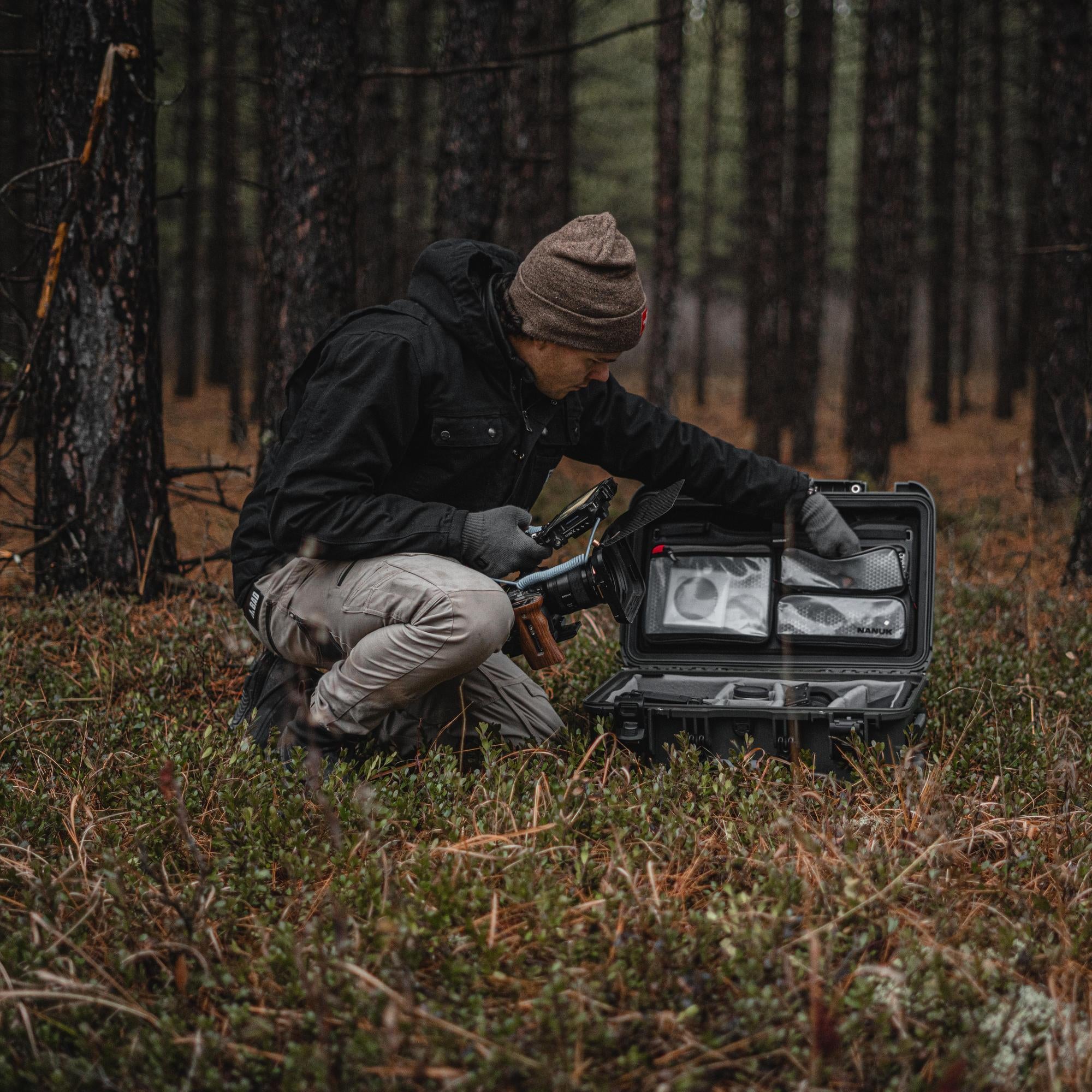 Person in a forest setting with a case containing equipment