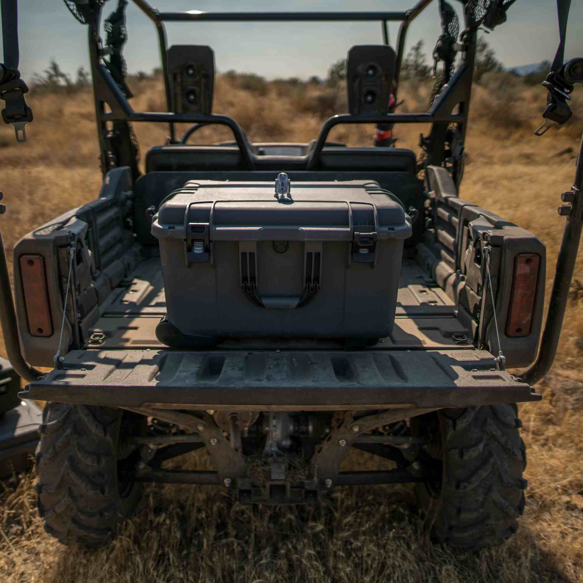 Gray NANUK storage case on the back of a four-wheeler in a field