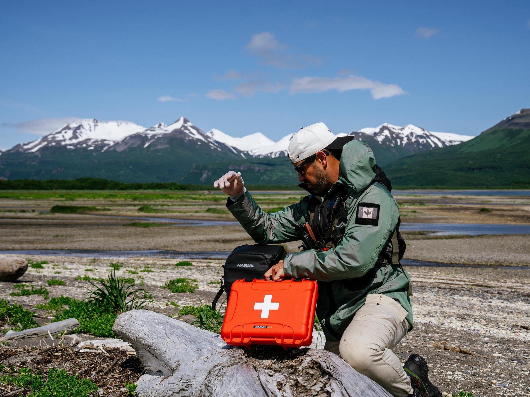 Person with a red急救箱 (first aid kit) in a mountainous landscape