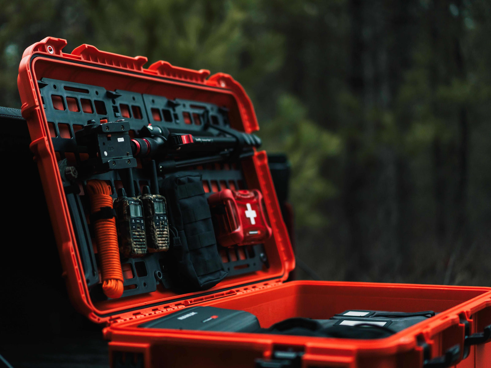 Open red tool case with tools inside against a blurred green background