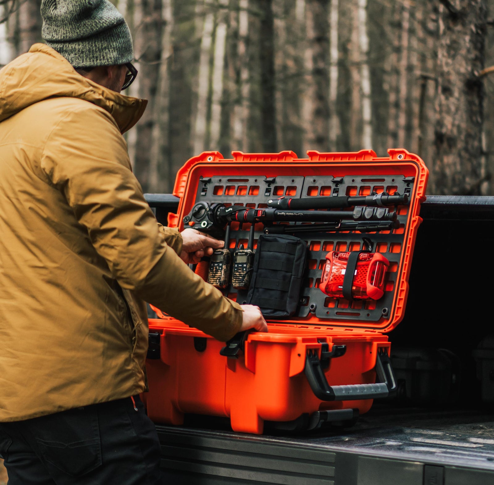 Person opening an orange toolbox in a forest setting