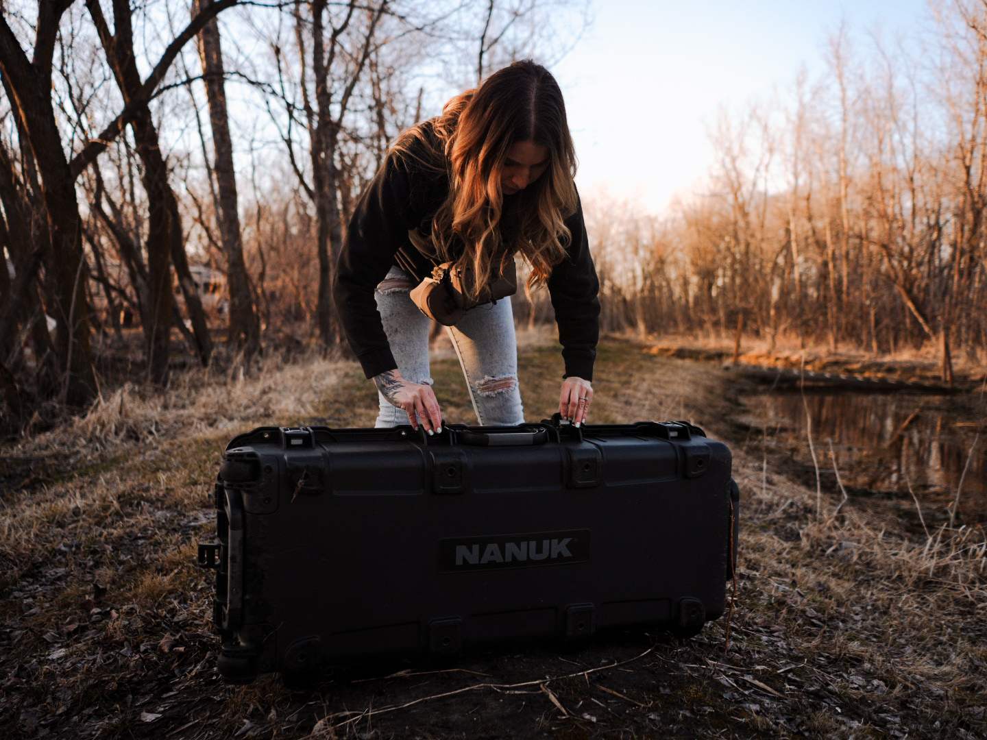 Person interacting with a NANUK case in a forest setting