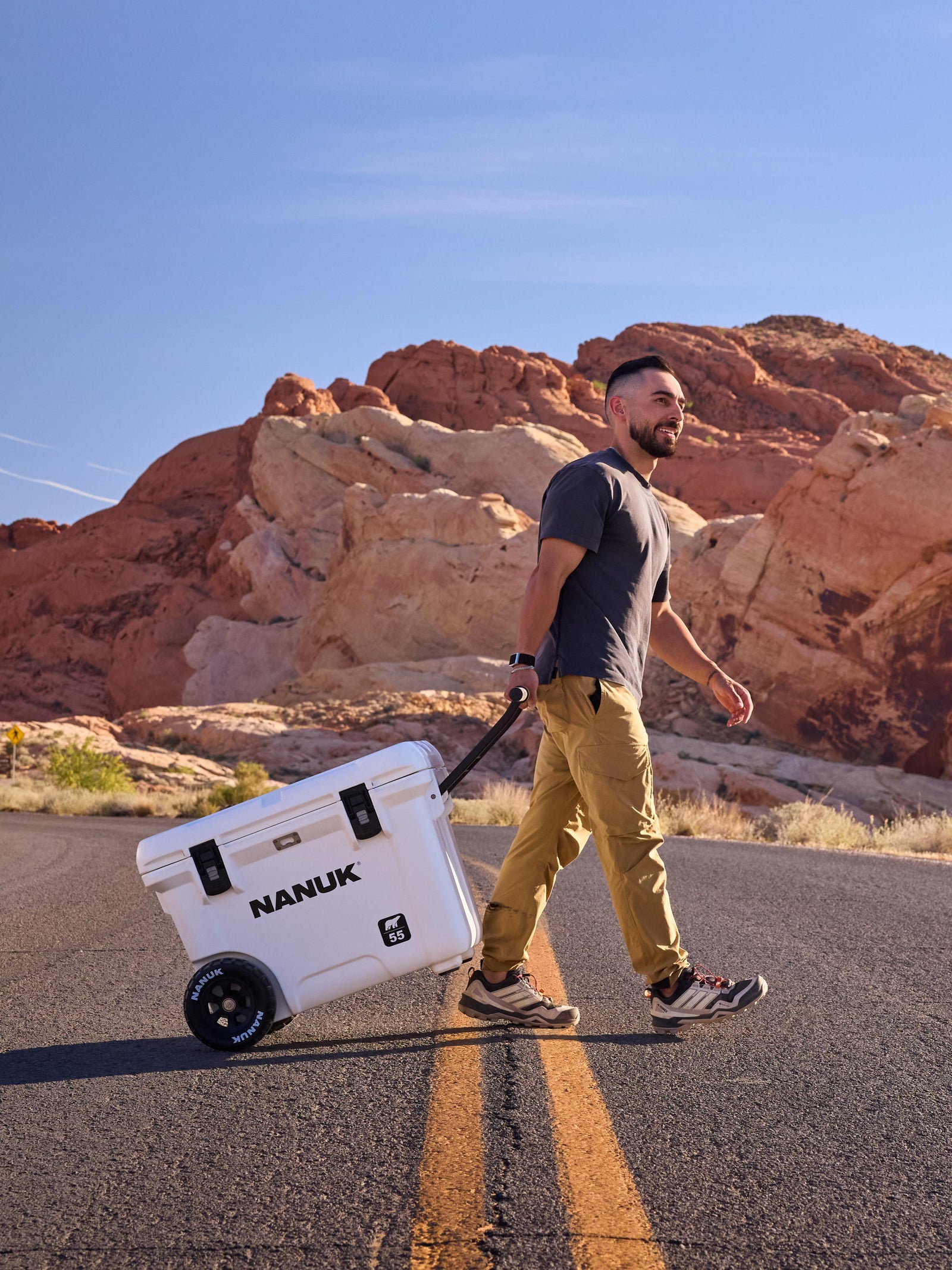 Man walking with a Nanuk cooler in a desert landscape