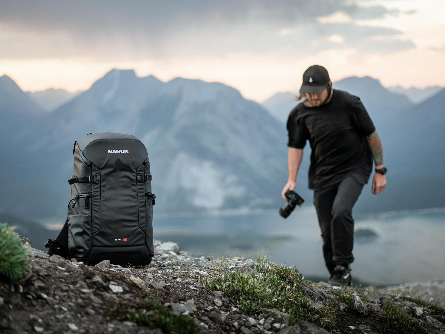 Man with backpack and camera in mountainous landscape