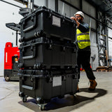 Three Nanuk 976 stacked up and rolled by a construction worker in a warehouse