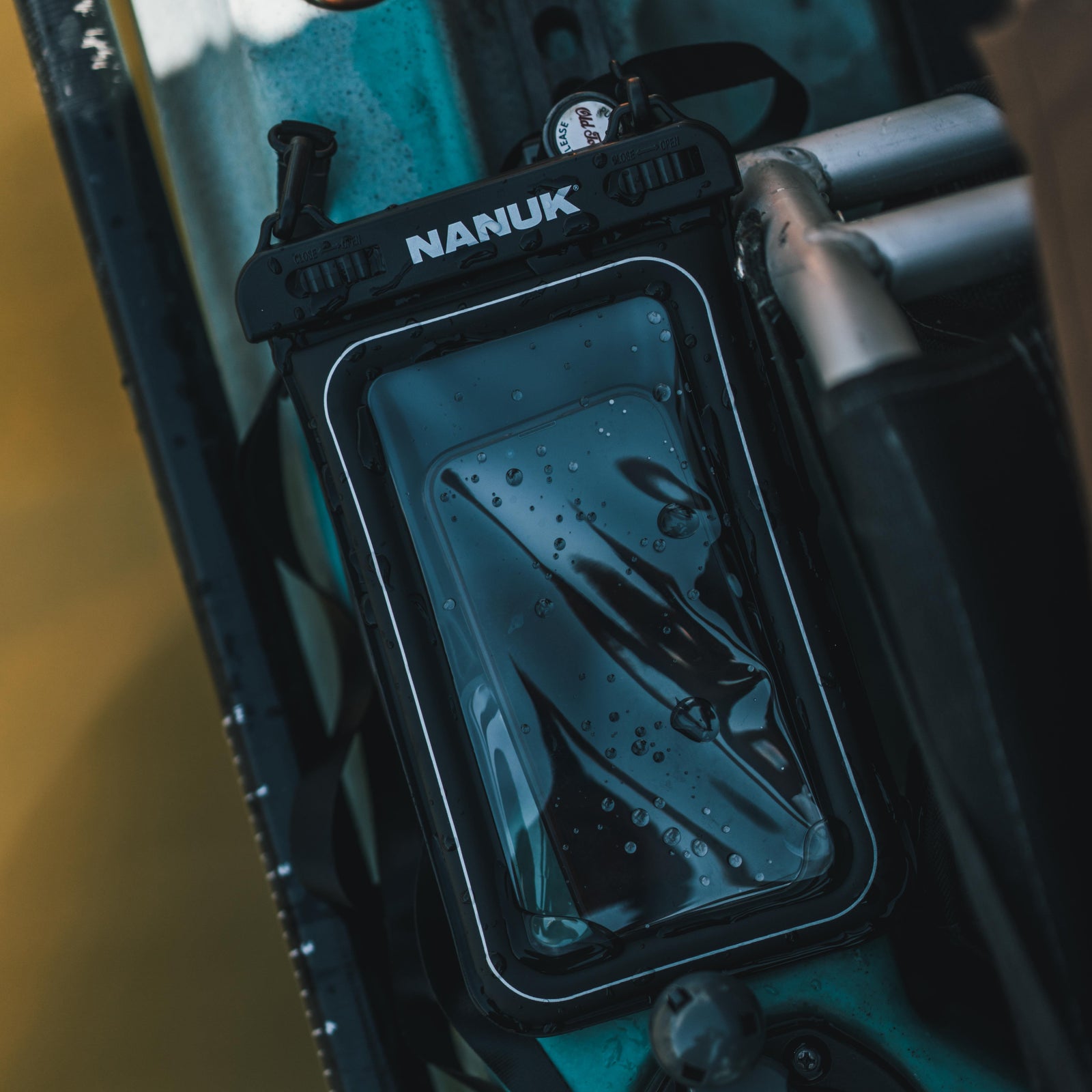 Nanuk phone case attached to a vehicle, with water droplets on the phone screen.