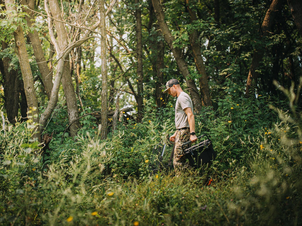 Man walking through a forest carrying a backpack