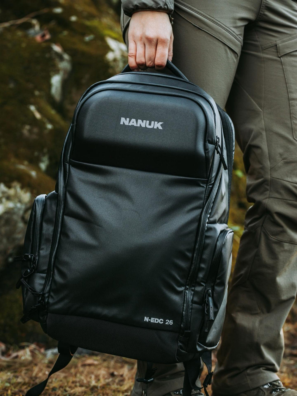 Person holding a black Nanuk backpack in an outdoor setting