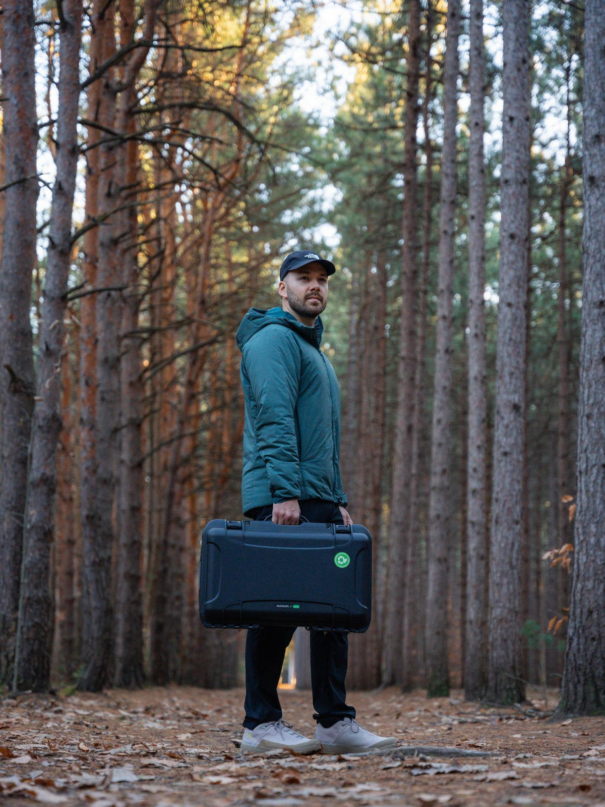Man holding a large black case in a forest