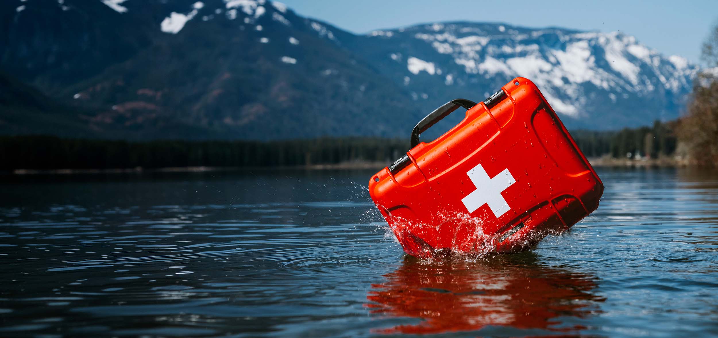 A red First Aid Case drops in the water