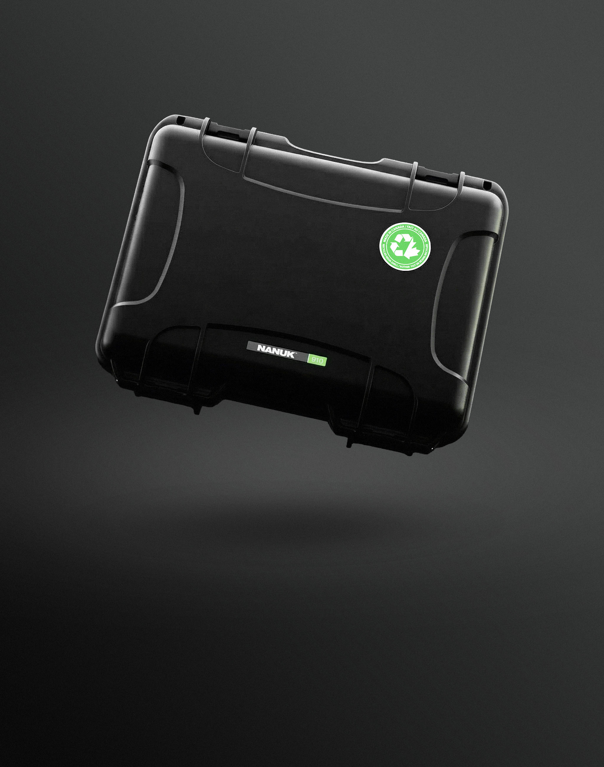 A black Nanuk 910 recycled resin case with a prominent green recycling sticker floats against a dark grey background, showcasing eco-friendly Nanuk cases.