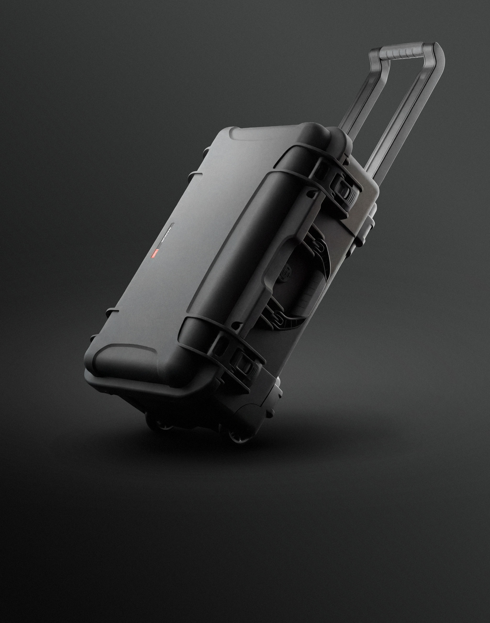 A durable black wheeled case, characteristic of Nanuk cases, is dynamically presented with an extended handle on a dark background.